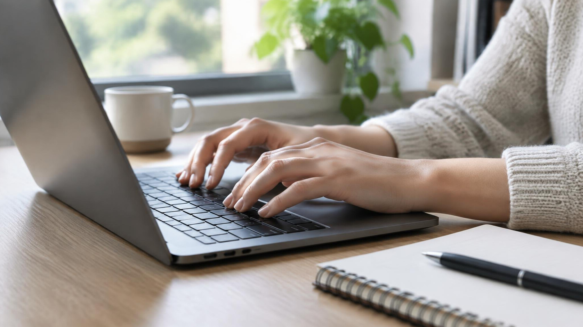 Close-up of hands typing on a laptop keyboard while editing video